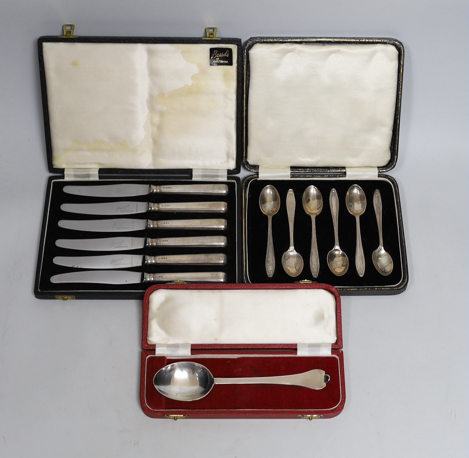 Three cased sets of silver flatware including a 1953 Commemorative dog nose spoon, six teaspoons and six tea knives.
